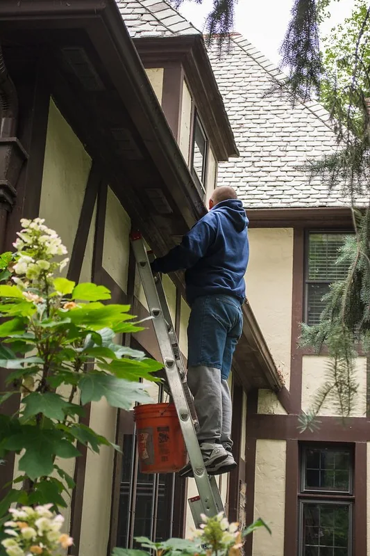 Worker on a ladder clearing a home’s gutter
